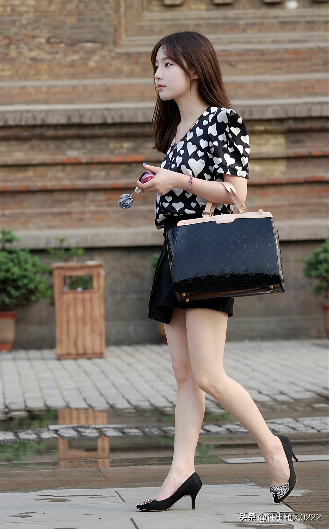 优雅漫步，黑白波点裙搭配黑色高跟鞋，手拿包包，尽显时尚魅力