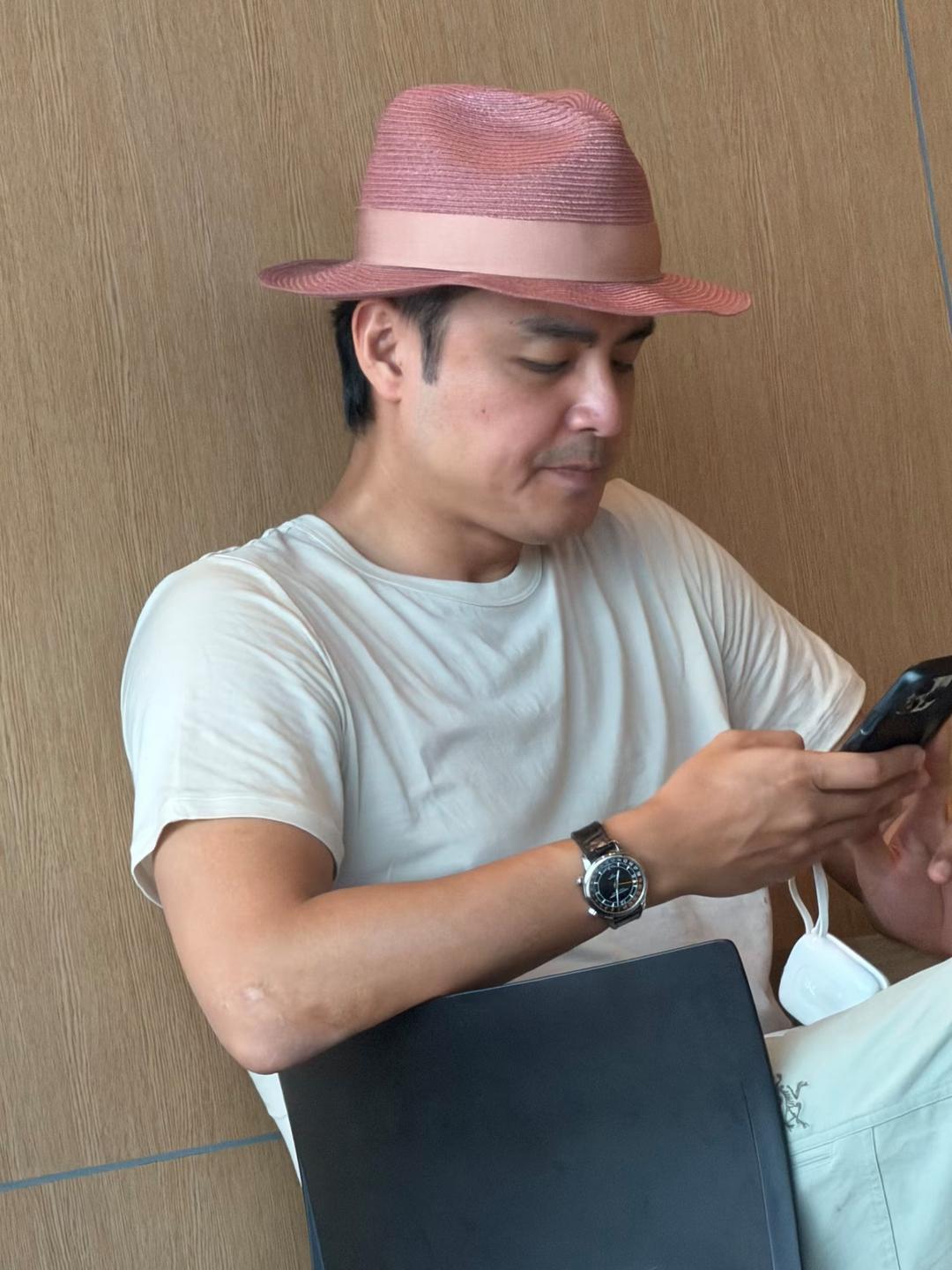 明道头戴玫红色礼帽现身上海一家餐馆，他端坐在椅子上，一身清凉的白色装，裤子上的始