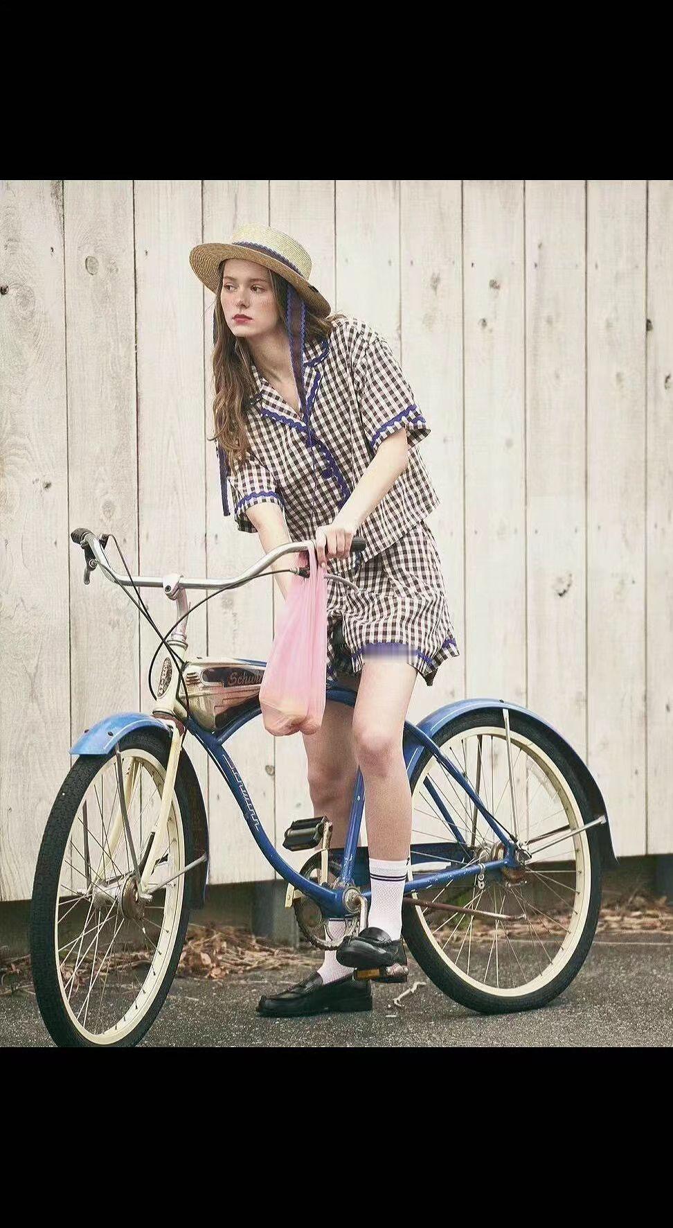 🚲草帽被风吻出褶皱，蓝单车驮着整个夏天🍃。格子裙摆晃成流动的诗，粉袋里藏着刚