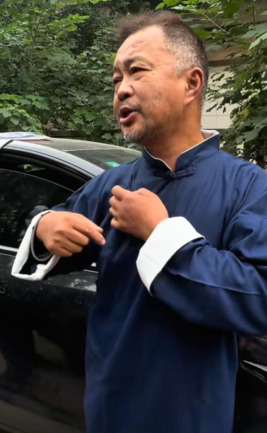 沈巍打扮成孔乙己的模样，一些靠他起号的人对他前簇后拥。
整天围着他、靠他养活的那