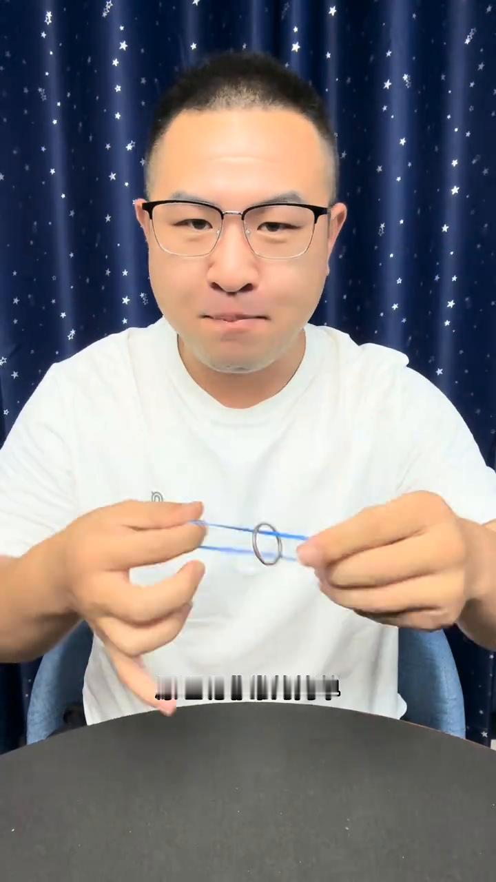 揭秘铁圈穿越术。
大家好，我们来看一下橡皮筋上有一个铁环，它可以跑上去跑下来，这