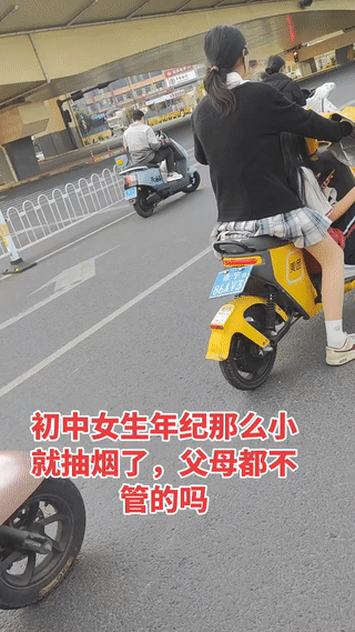 街头拍到两个正在骑车等红灯的初中女生。
其中有一个女生竟然还在抽烟？
一个女孩子