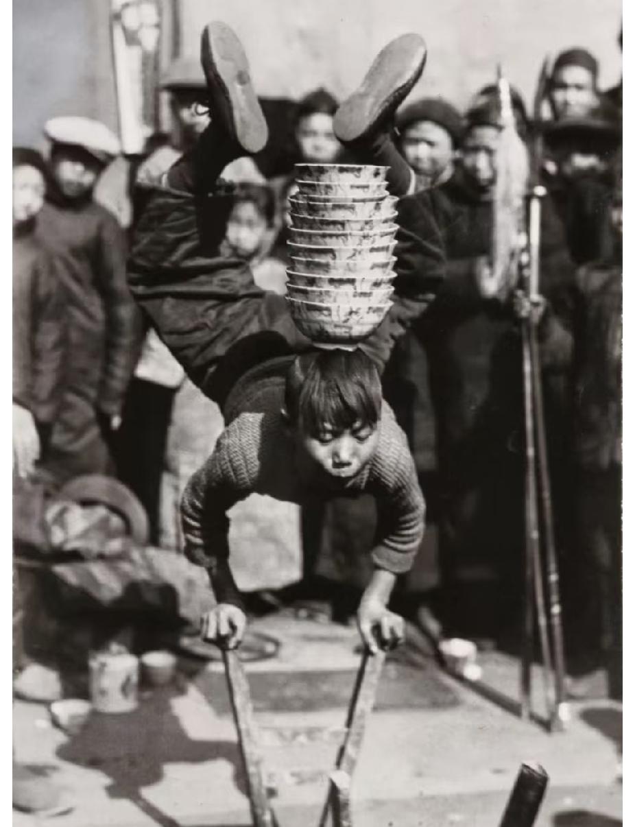 这张照片拍摄于1929年，地点在浙江街头。镜头中央是一名年幼的男孩，依靠两根木棍