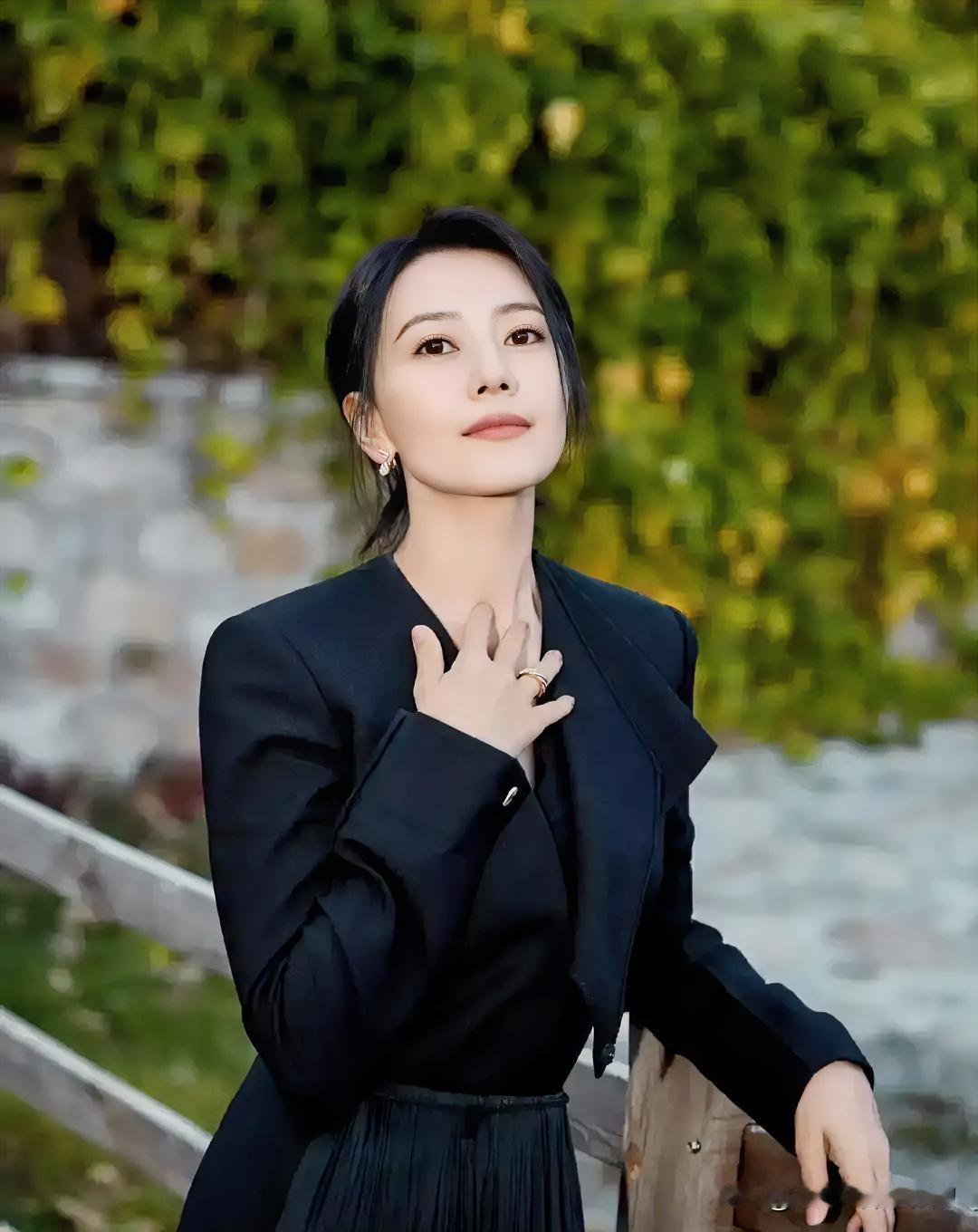 黑色大衣自带沉稳气场，于秋日光影中轻抚衣襟，优雅姿态尽显独立女性的从容与知性魅力