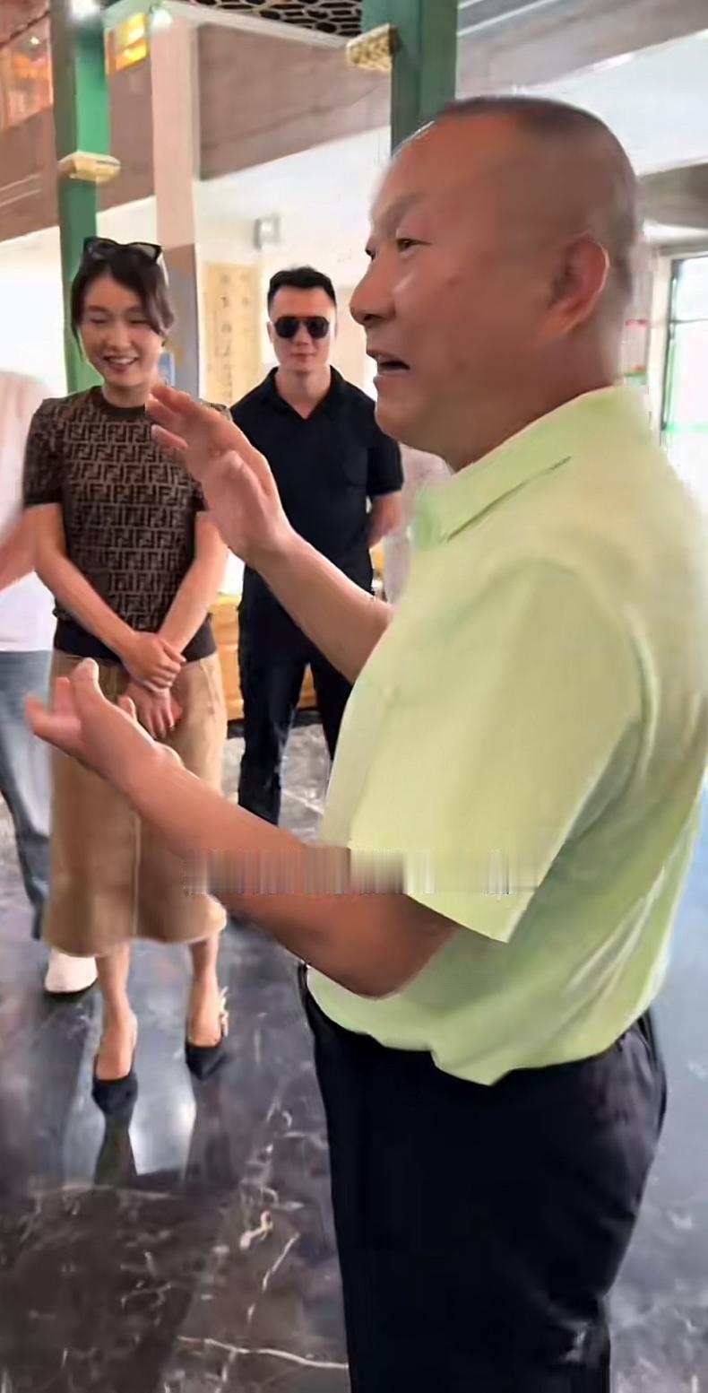 北京坤哥的保镖，戴着一个黑色墨镜，站在河南信阳大网红刘文新旁边。刘文新正在和北京