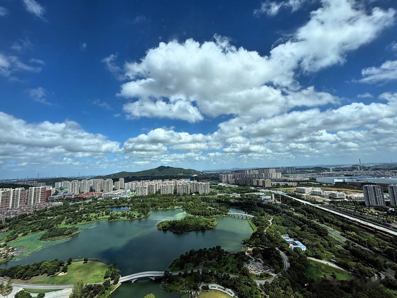 蓝天白云下，城市绿意盎然。
坐标南京，俯瞰仙林湖，远眺栖霞山，能看到长江上运船来