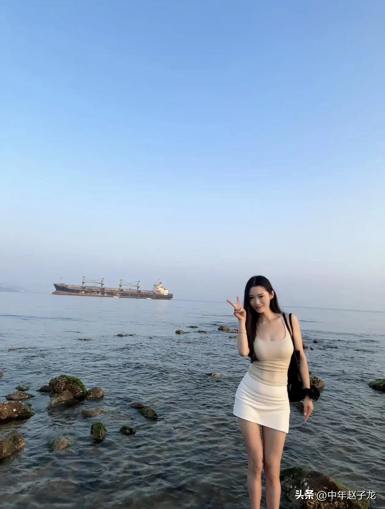 浅蓝晴空铺在海面之上，零星礁石从清透的浅滩露出头，远处搁浅的巨型货轮静静浮在水天