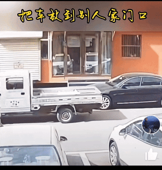 一辆新车停在一个商铺门前路上，影响了商铺经营，商铺店主开来一辆小货车，用货车尾来