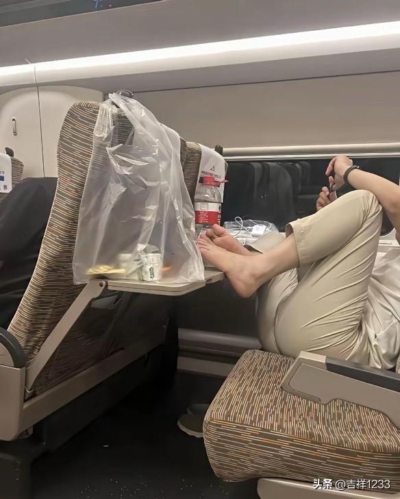 哥们这是高铁车厢，你的脚丫子踩在餐桌板上不好吧？这是旅客吃饭用到小桌板，你这个半