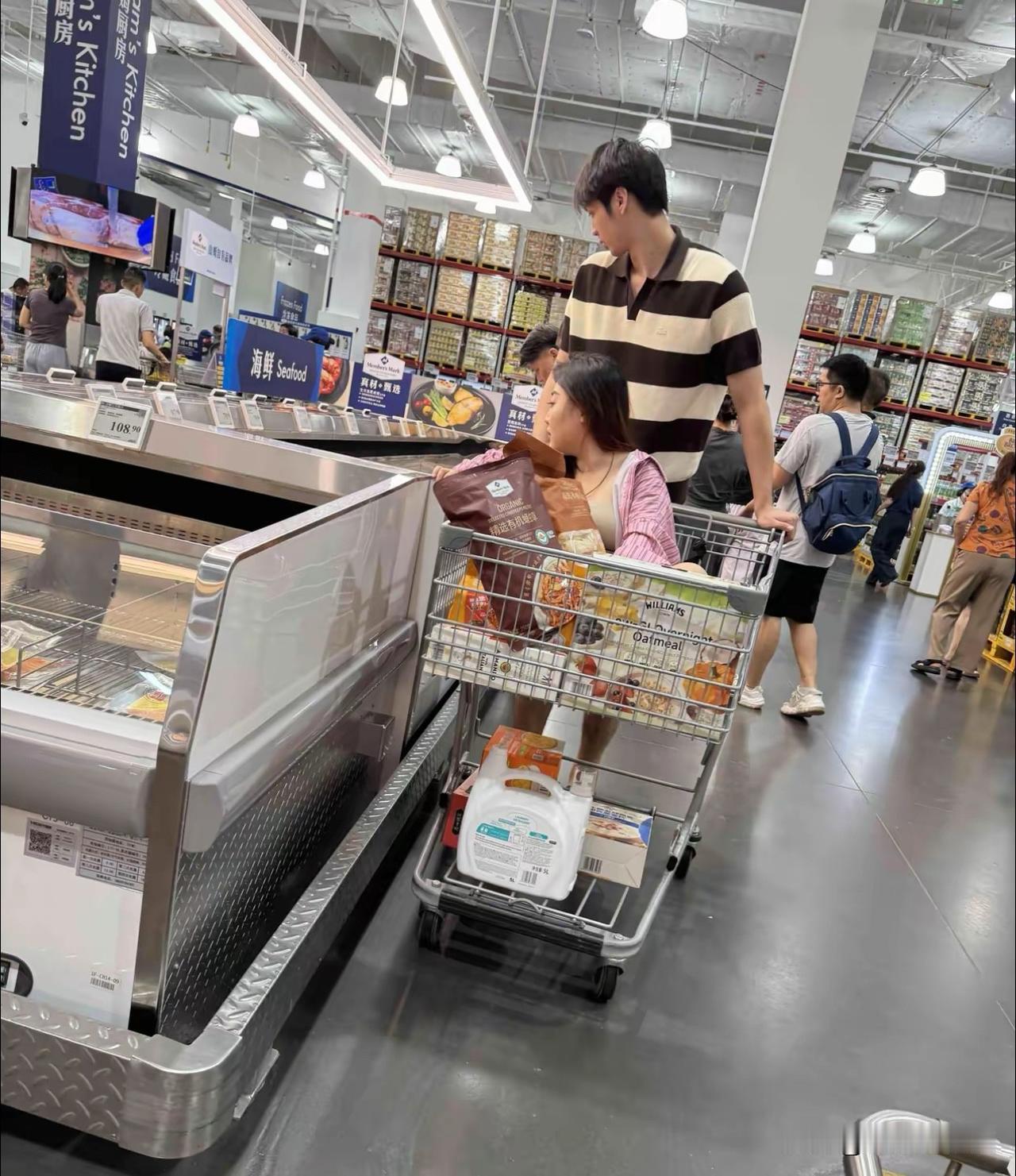 山姆超市，偶遇这一幕，这啥情况呀？
一成年女子像婴儿坐在购物车里，
一帅小伙子推