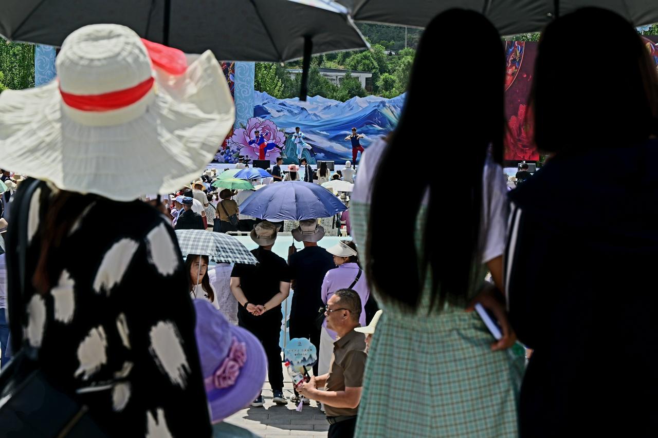正午烈日当头，露天舞台之下，挤满前来观演的群众。骄阳炙烤着大地，炽烈的阳光铺洒在