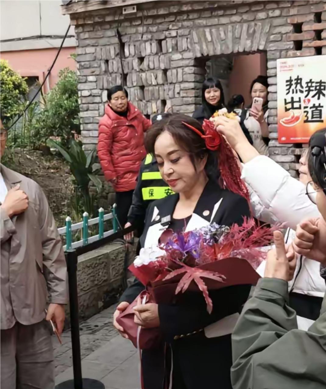 刘晓庆回重庆了，头戴鲜玫瑰花，和小红椒，手里拿着也是红辣椒，刘晓庆晓得合不拢嘴。