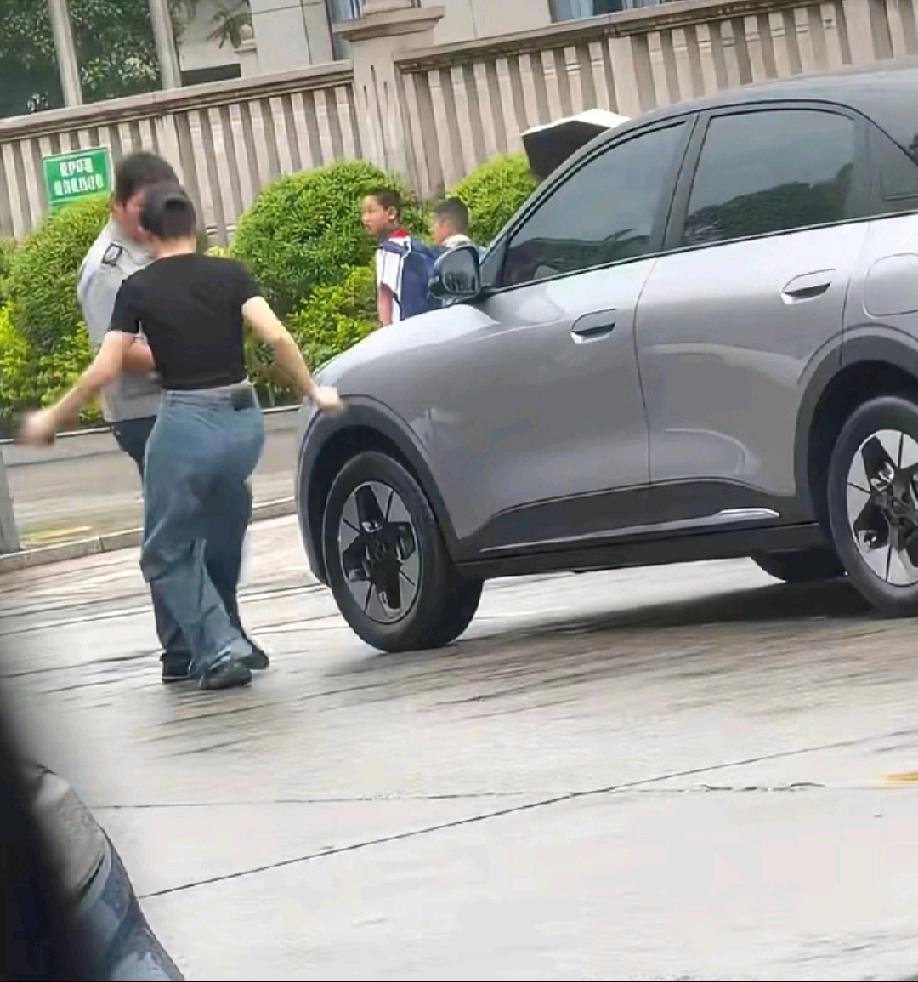 路人视角:疑似女车主和保安大哥发生争执，女车主对保安大哥抬腿一脚，保安大哥也不惯