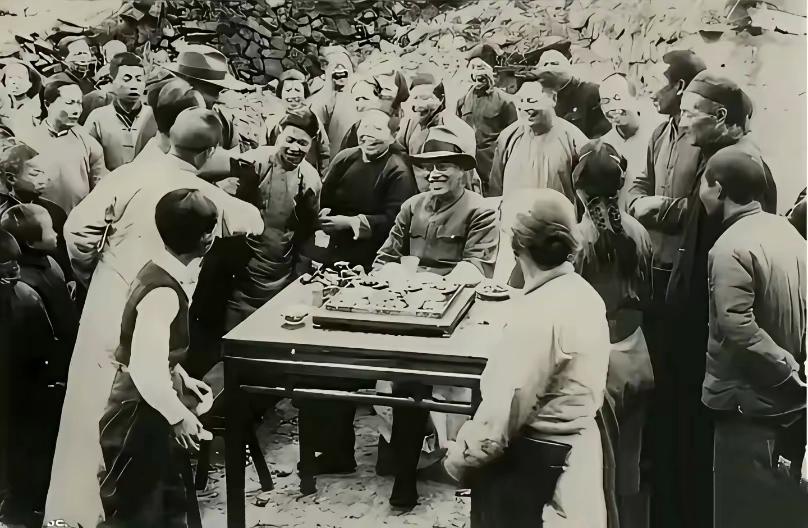 这是1947年蒋介石和其儿子蒋经国回老家，蒋介石坐在桌子前，被众人包围的照片。