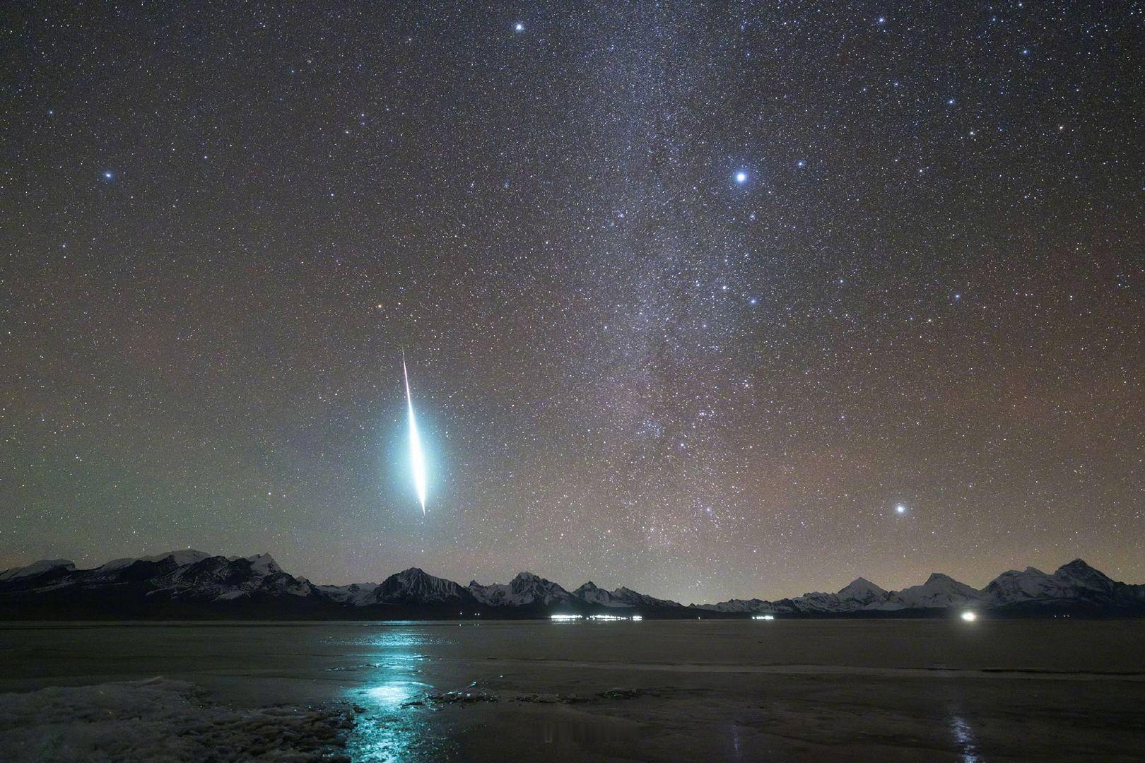 在银河的温柔怀抱中，一颗火流星如恋人的低语，划过夜空，绽放蓝绿色的光芒，直落入多