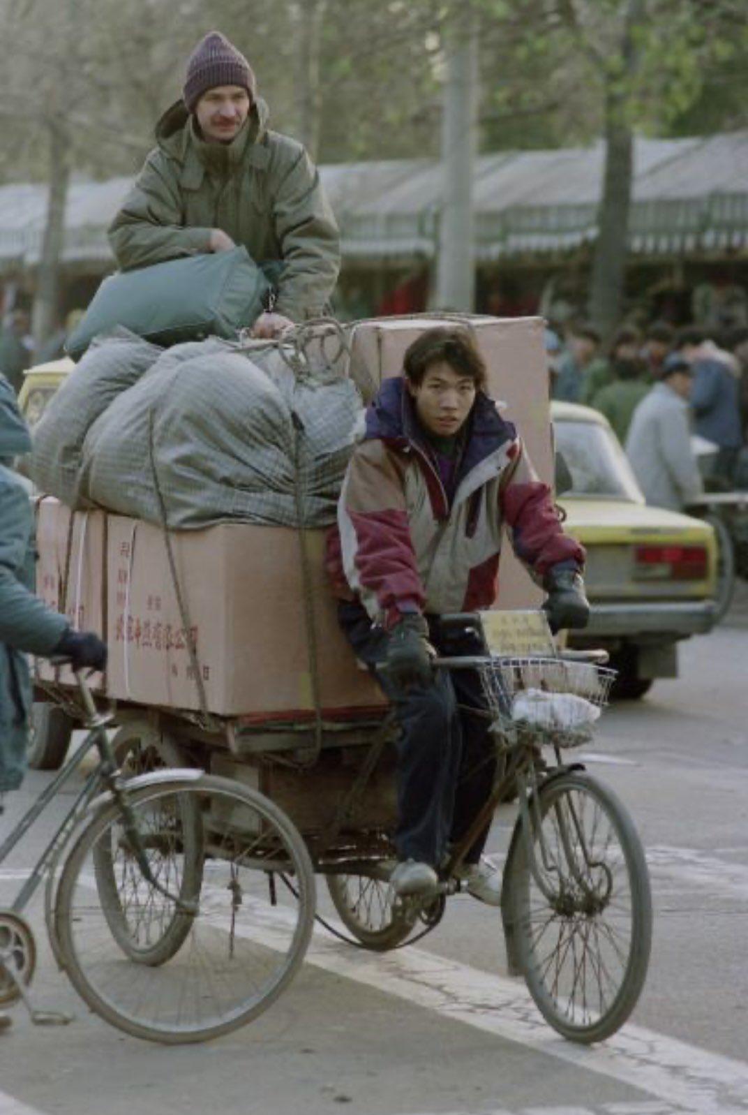 1993年11月18日，北京日坛公园市场内，一名俄罗斯商贩坐在自己采购的货物上。