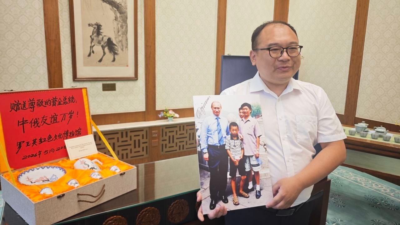 普京抱过的小男孩已成为工程师彭湃手持照片，旁边是普京送给他的茶具 