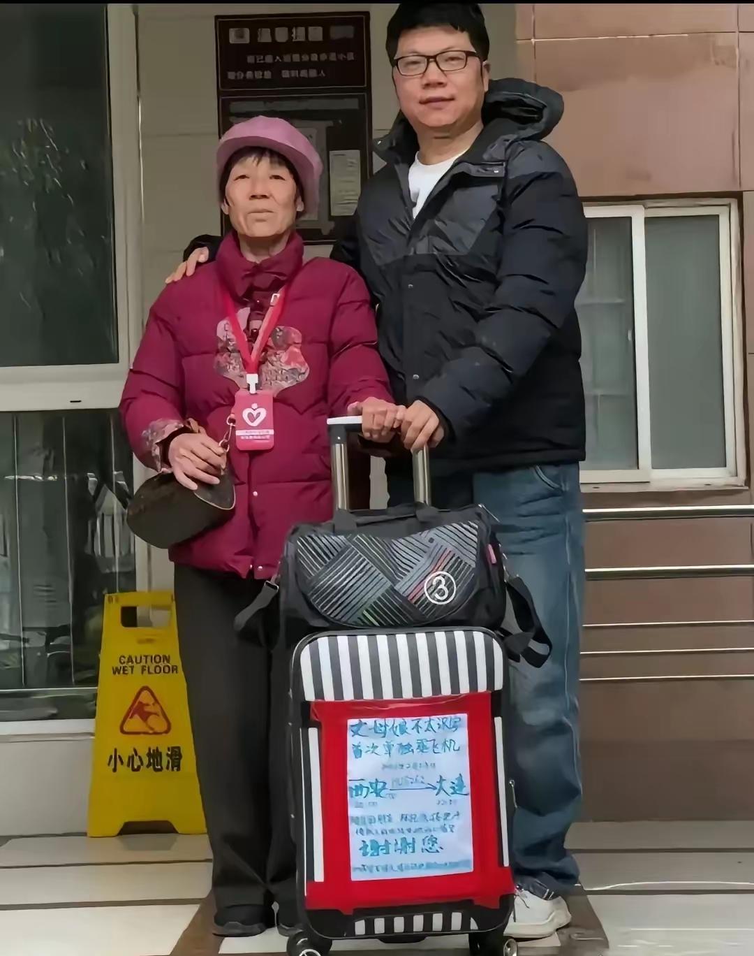 机场里，小伙子给丈母娘送行，老人的行李箱上贴着一张纯手工写的大海报，上面写着:“