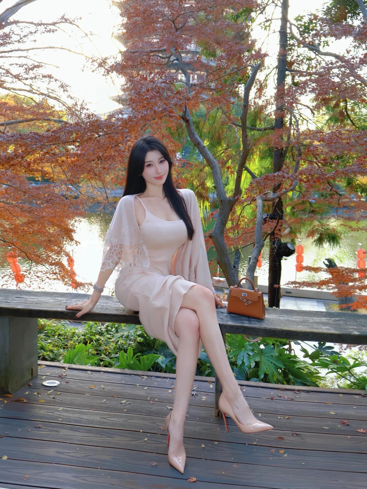 秋日暖阳下，优雅女子倚栏而坐，红叶映衬，美不胜收。