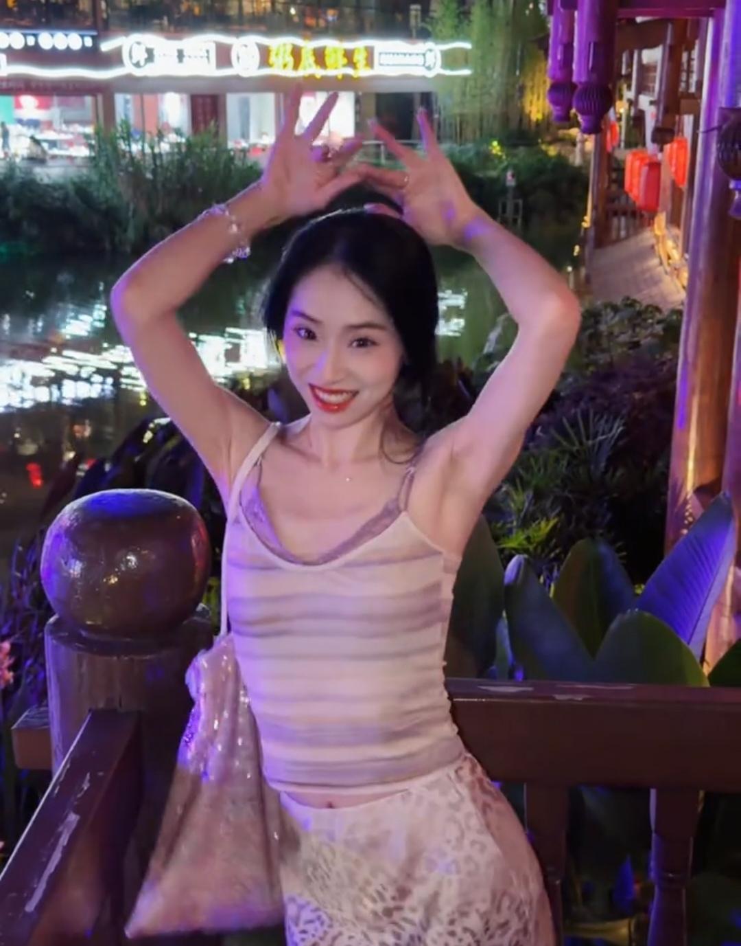 夜晚的河畔，少女俏皮地比出“耶”，灯光映照下，美不胜收！🌃✨👧💃