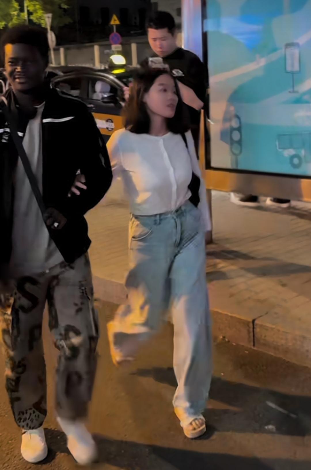 北京三里屯是时尚繁华之所。街拍中女友与非洲男友的合影，展现了中西文化交流，跨国情
