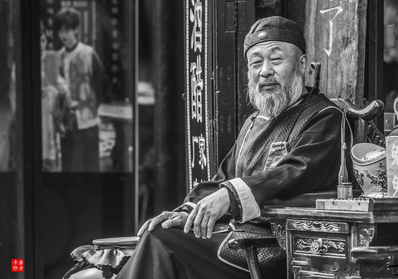 时光在他的眉间刻下了经纬，也在那花白的胡须里藏尽了春秋。静坐于老店门前，一身古韵