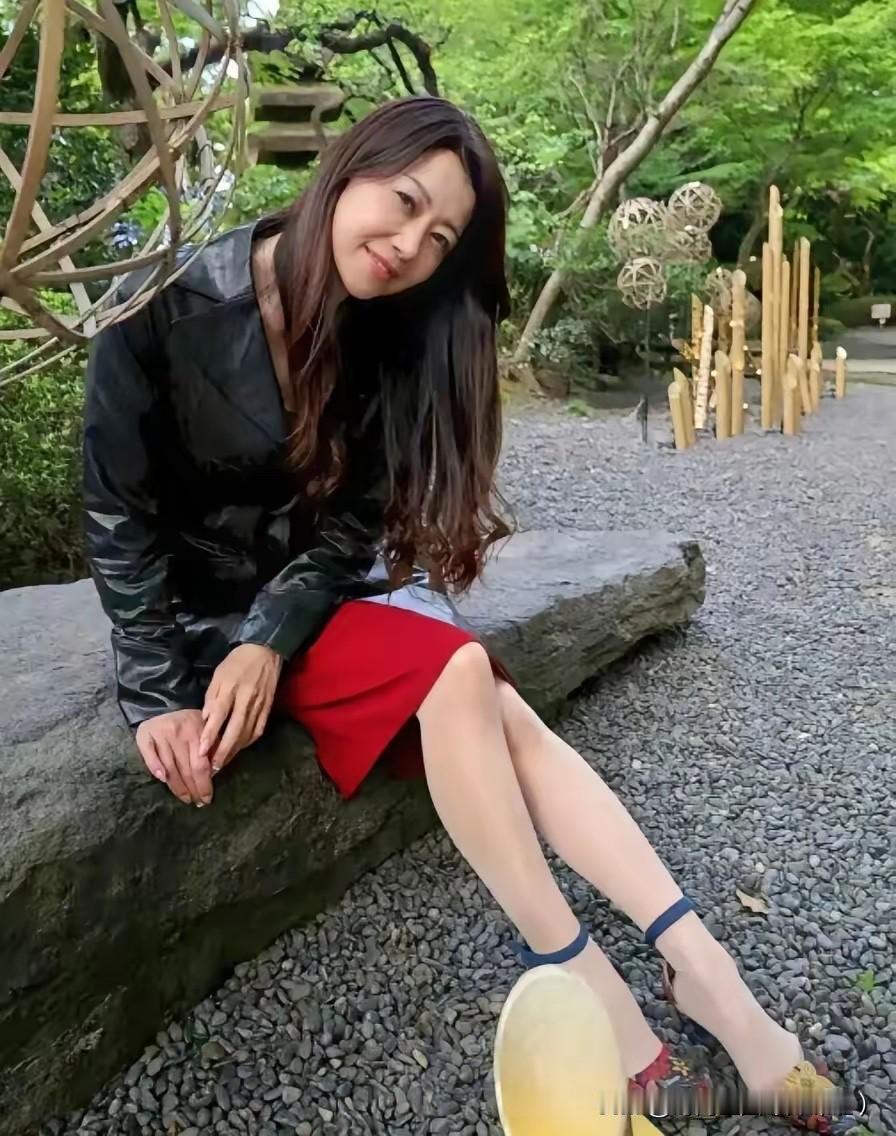 在绿意葱茏的庭院里，风都带着温柔的气息。
一身利落的黑皮衣搭配明艳红裙，就像把岁