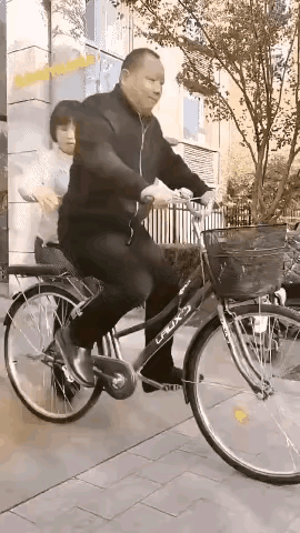 一位男人，骑着一辆自行车和老婆一起逛街，男人骑上自行车，蹬了几下，车跑了起来，老