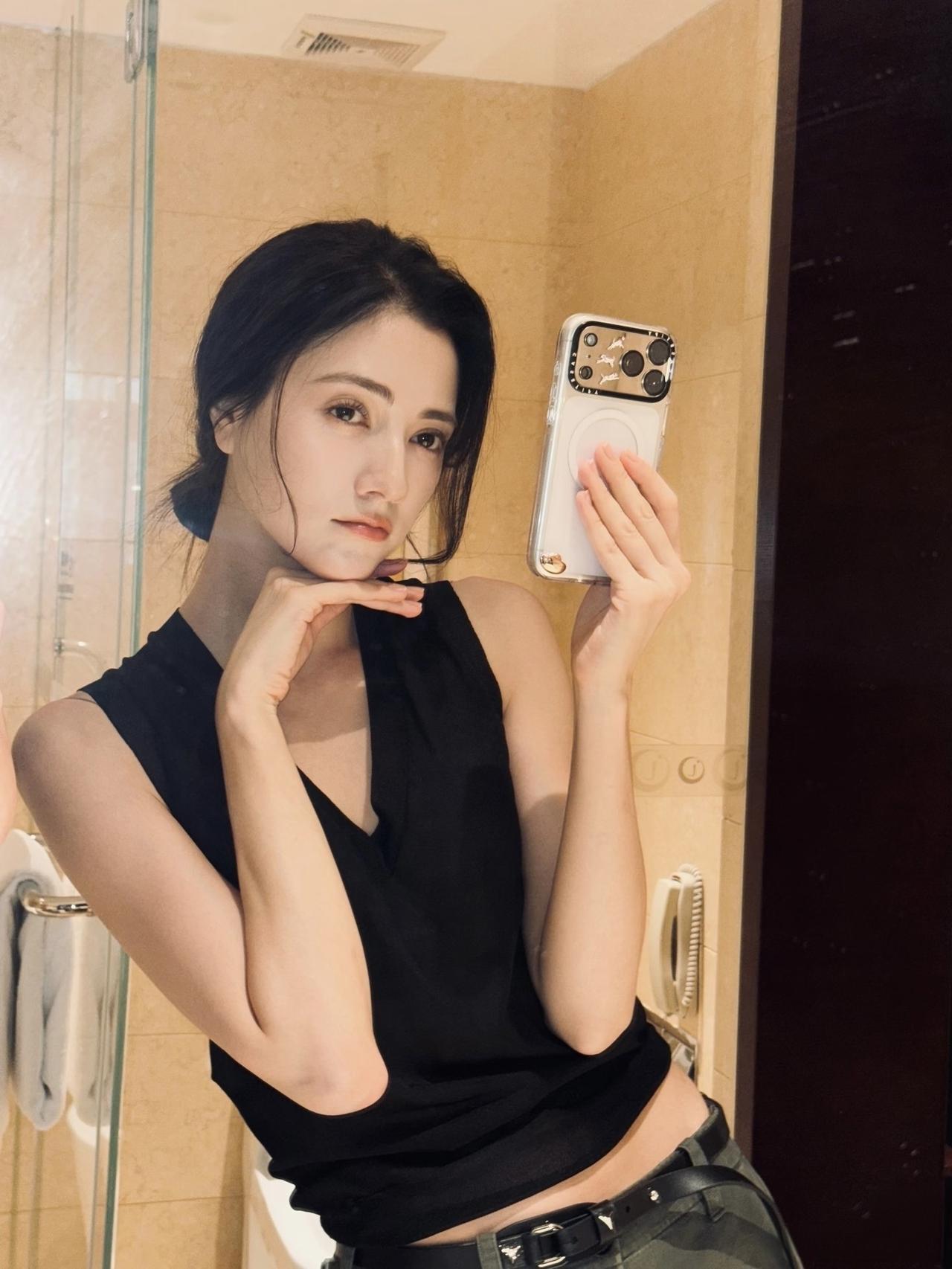 娜然黑色背心配低腰裤，
肚挤眼微露，
对着镜子各种姿势自拍，
非常自信，
看来对