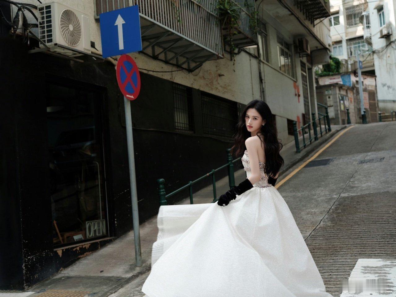 沈羽洁现实版落跑千金没错了 白色礼裙衬得她优雅灵动，海藻长发氛围感拉满！小巷背景
