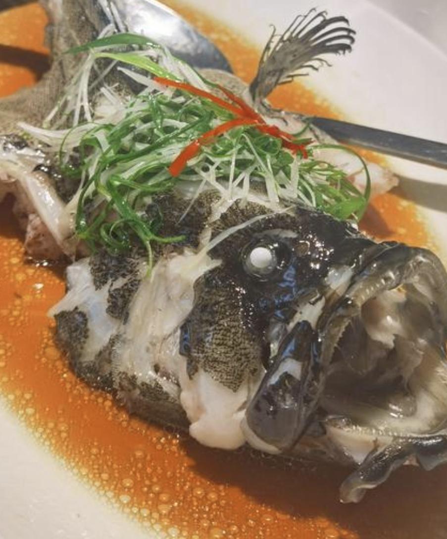 清蒸鲈鱼上桌时，盘底只铺一层薄如蝉翼的姜丝，鱼身却像刚从月光里捞起的银梭，闪着冷