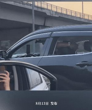 男子坐在车里，双手把着椅背，悠闲地看着手机。
估计他是把车设计到了自动驾驶的模式