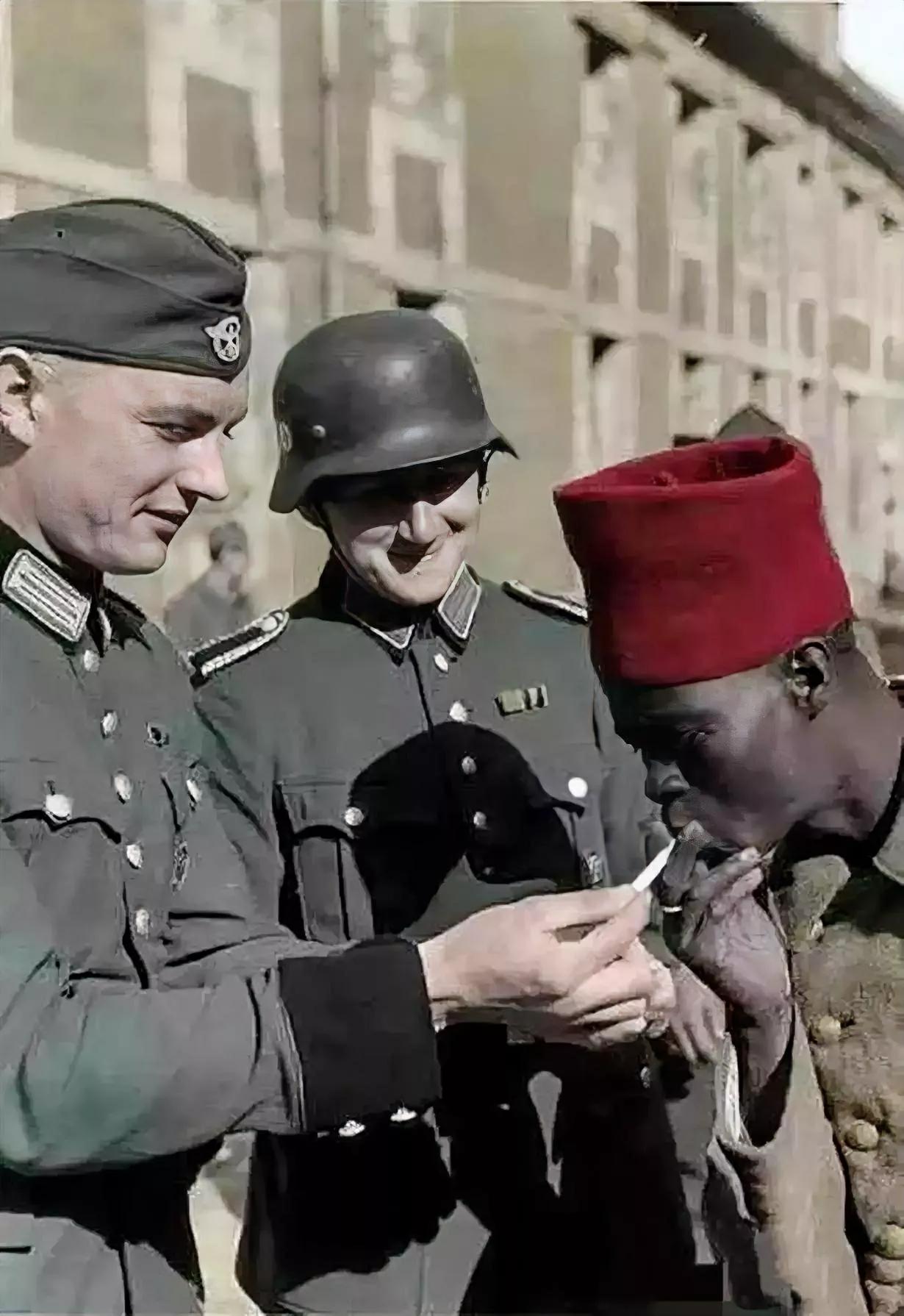 1940年，法国巴黎，德军正为法军战俘点烟。这名法军来自法属非洲殖民区，战斗力堪