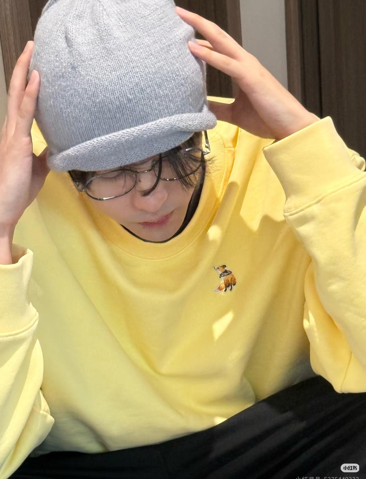 亮黄色连帽卫衣，配以冷帽、金丝边眼镜及微长发型，整体造型兼具潮流感与居家男友风，