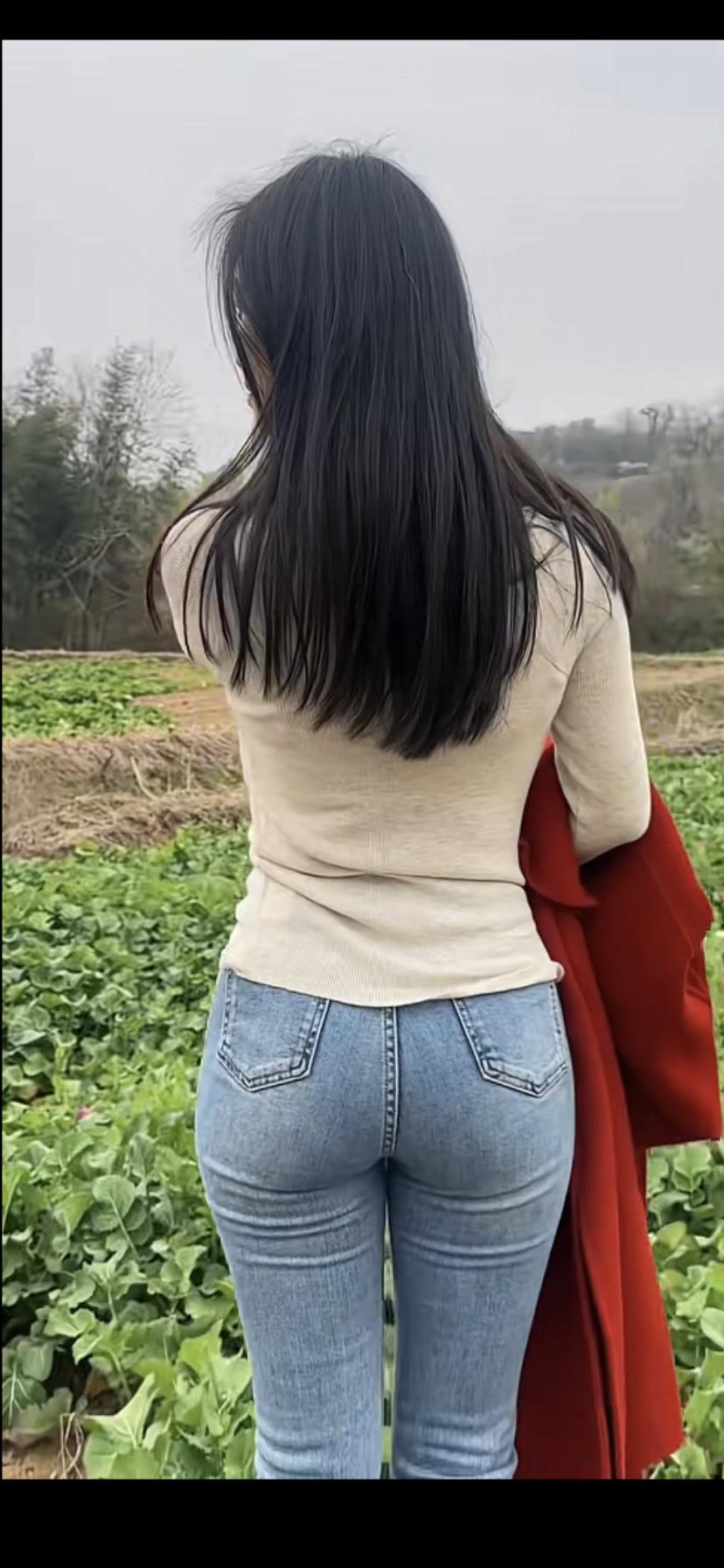 背对镜头，长发飘逸，红衣点缀，绿意盎然。