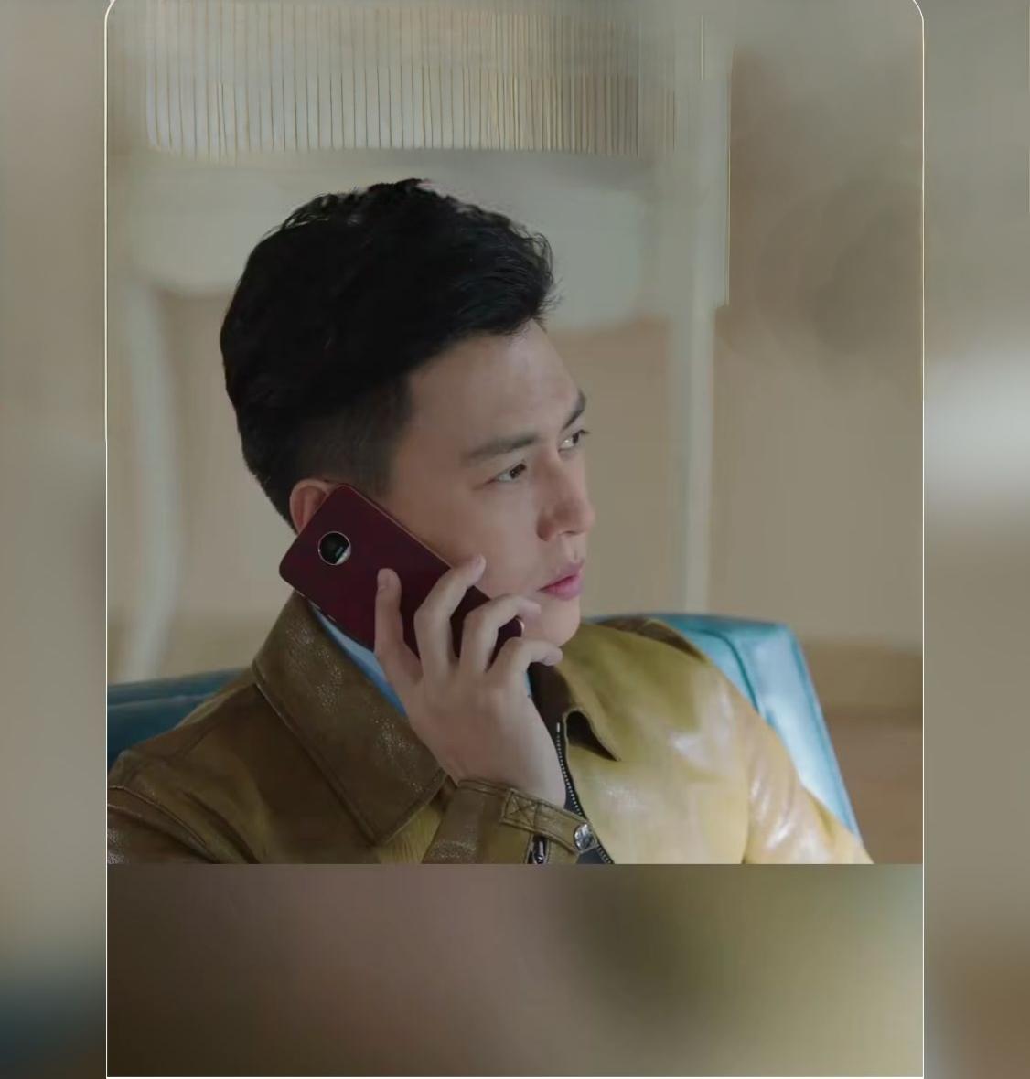 靳东一身复古黄皮衣，打电话时神情沉稳专注。眉眼自带成熟男人的气场，冷静又有故事感