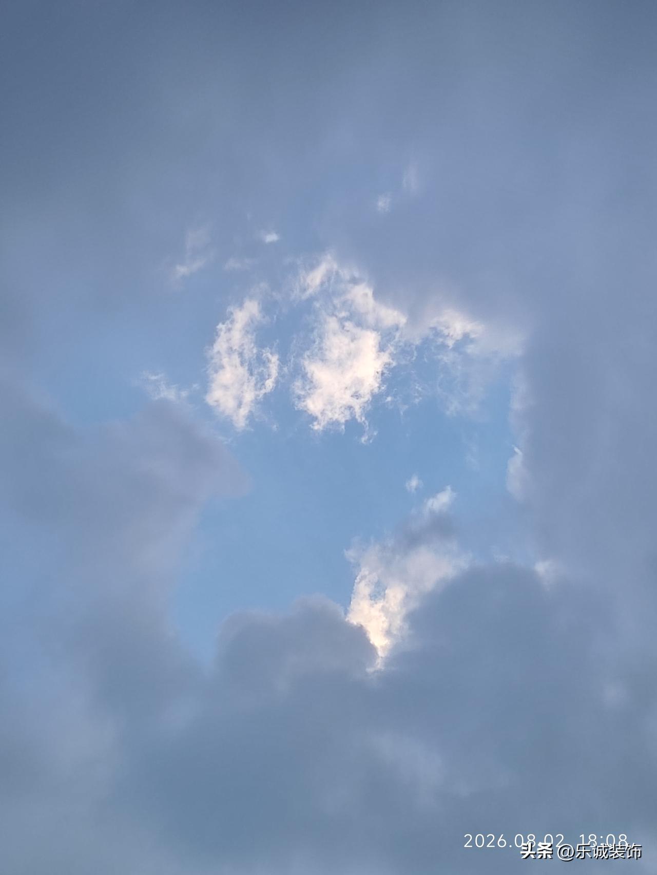 傍晚的天空温柔得不像话，大片浅灰云层舒展铺开，中间漏出一片澄澈清蓝。几缕薄云被落