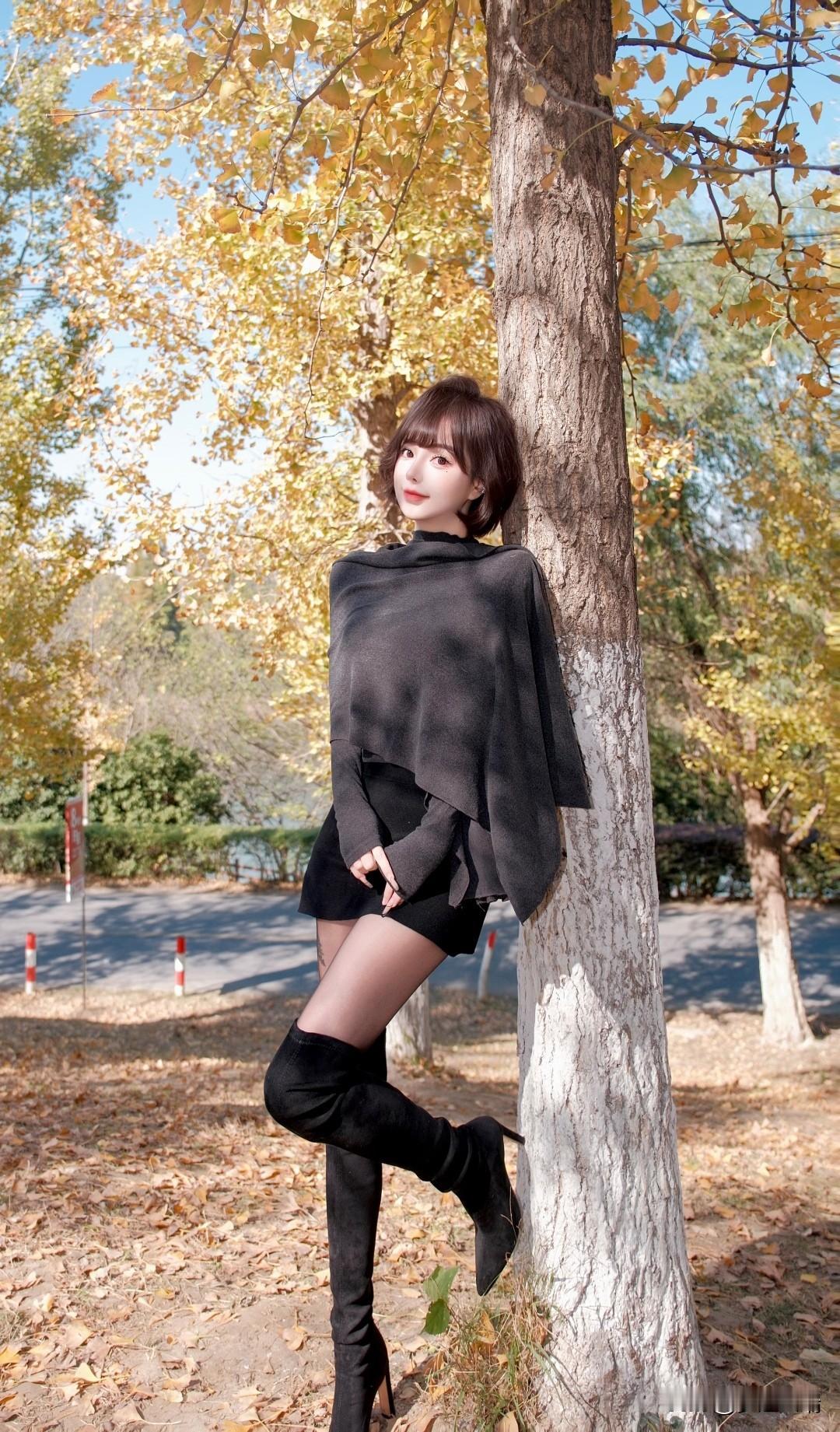 秋日暖阳下，树影婆娑，她倚树而立，优雅动人。