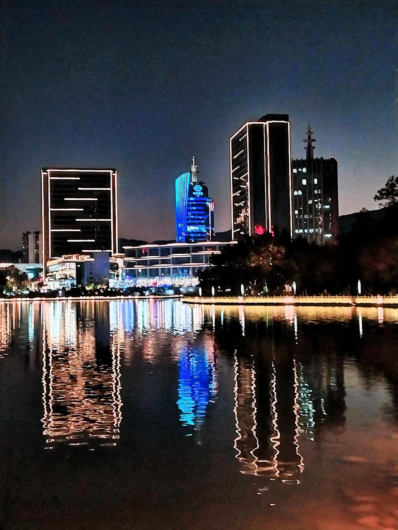 夜幕下的城市倒影，灯火辉煌，美不胜收！🌃✨漫步在公园的小径上，身旁的湖水宛如一