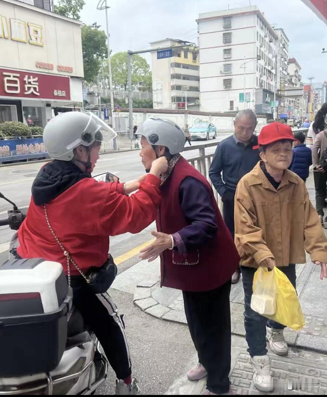 街头暖心一幕：女儿温柔为老母亲戴头盔

今天中午下班偶遇特别温馨的一幕，一对母女