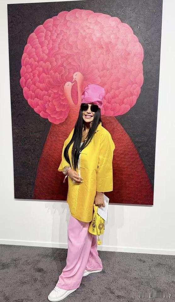 杨二车娜姆去迪拜看展，这次不戴大帽子而是绑头巾。当天她穿着玫瑰粉的头纱和同色系的