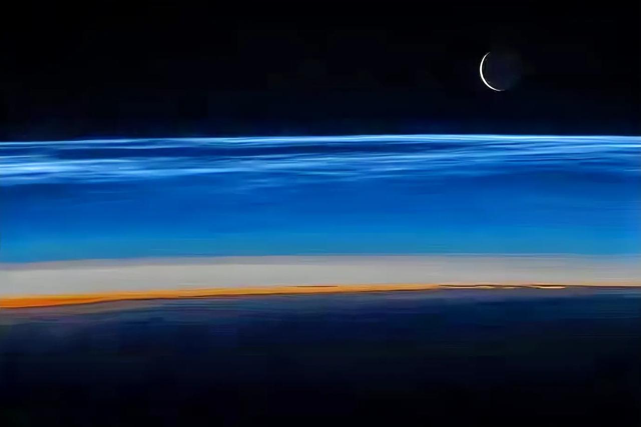 从太空看一轮残月从天边蔚蓝色的大气层上升起，这张照片是国际空间站上的宇航员Mat