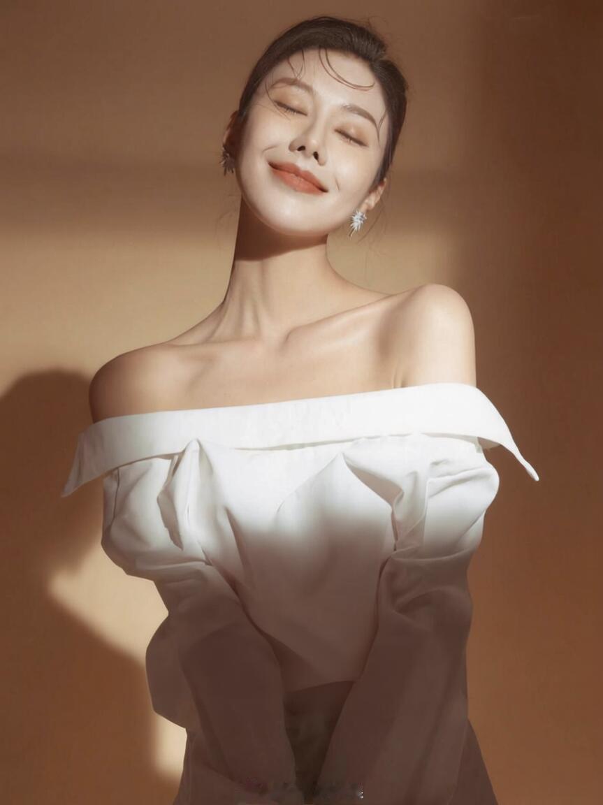 暖调光影裁开柔白衣袂，指尖轻扬拢住一束光，睫羽垂落的瞬间，鎏金轮廓吻上肩颈，清冷