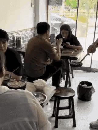 饭店内，服务员给顾客的小砂锅里面，加上很多的辣椒，看着很香，辣椒油的味道很浓。