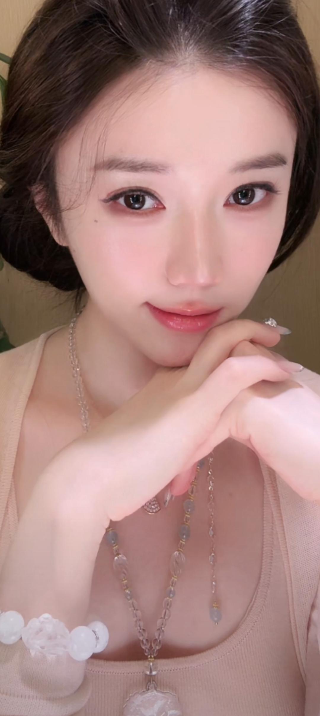这位美女正在微笑，手托着下巴。