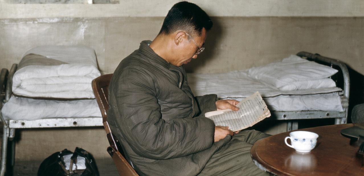 清朝末代皇帝爱新觉罗·溥仪在抚顺战犯管理所的改造瞬间，他正低头阅读自己撰写的交代