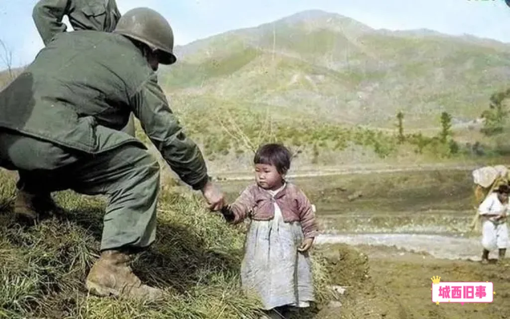 朝鲜战争时期，一名美国士兵正给一个朝鲜女孩递糖果，显然是希望通过这种方...