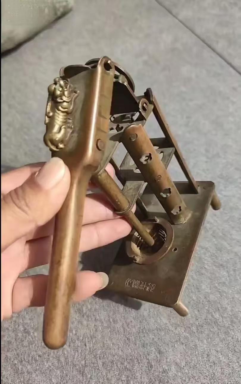 中午婆婆去卖纸皮，回来的时候手里提个这东西，铜的，棕黄色包浆，长柄上趴着个小兽，