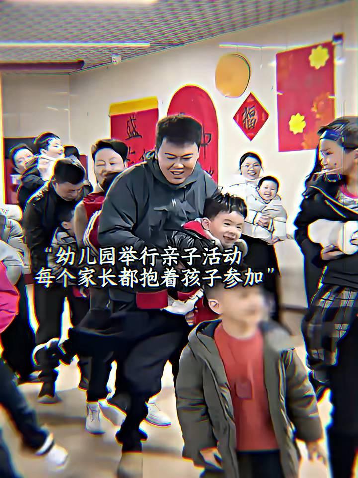 幼儿园举行亲子活动，每个家长都抱着孩子参加，人群中却有一个落单的男孩羡慕的看着其