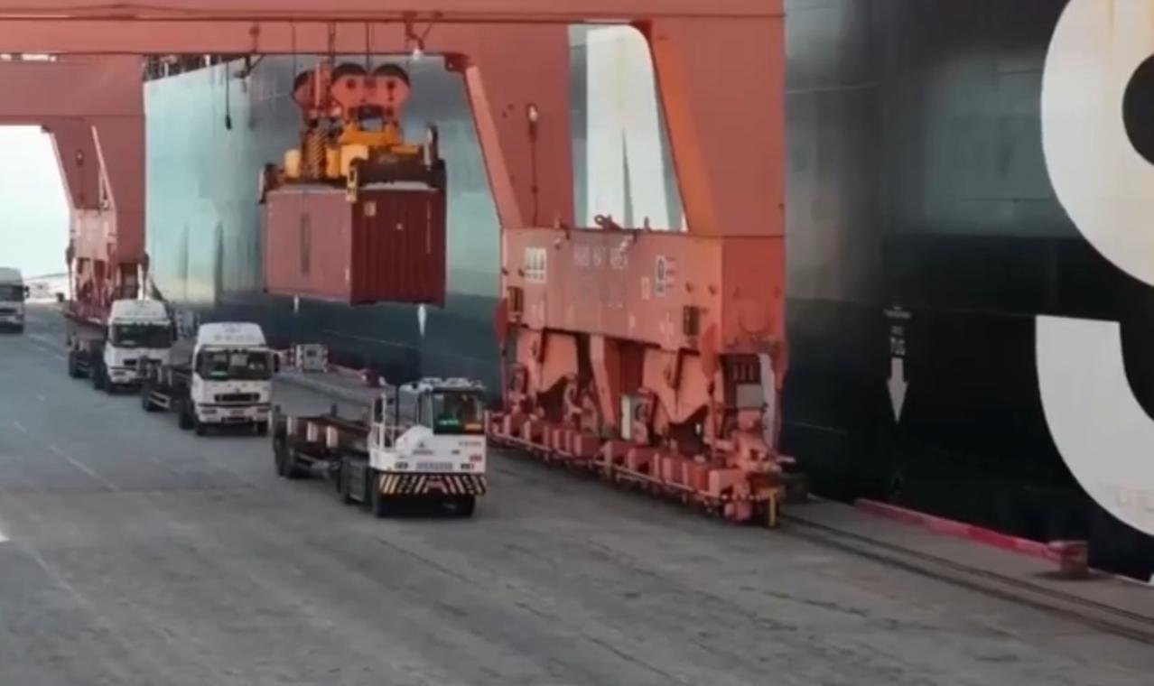 港口的红色吊机吊运着集装箱，货车穿梭间勾勒出海洋贸易的繁忙图景；深蓝海面上，巨型